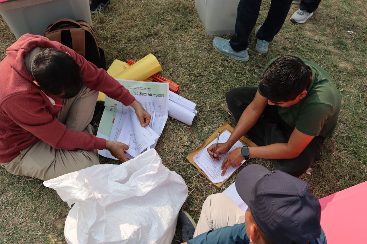 services-02 Election officials organizing ballots in an outdoor setting in Nepal, highlighting the electoral process.