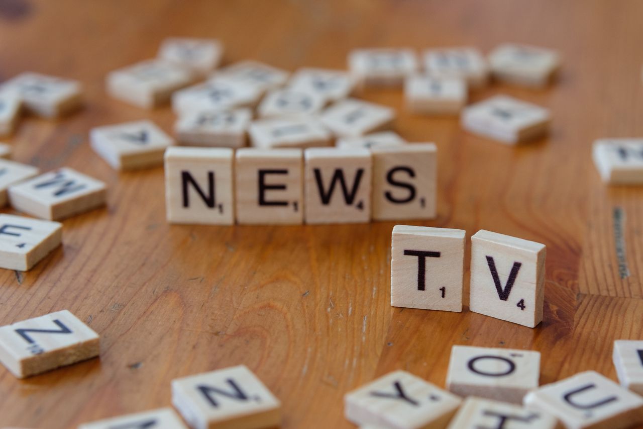 why-choose-us Close-up of Scrabble tiles spelling News and TV on a wooden surface.